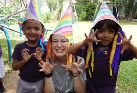 Volunteer Care A childcare volunteer in Sri Lanka runs a creative arts and crafts lesson, teaching children to make colourful hats.